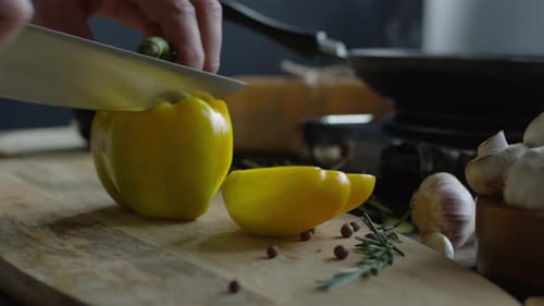 Chef cuts a yellow bell pepper on cutting board