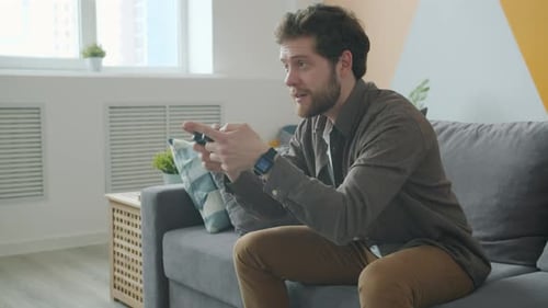 Young Adult Male Gaming on Couch Indoors