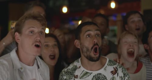 Sports enthusiasts cheering and embracing while watching televised match in bar, slow motion