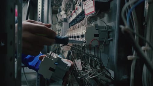 Electrical technician works at switch box. Hand with screwdriver. Electrician is checking connection