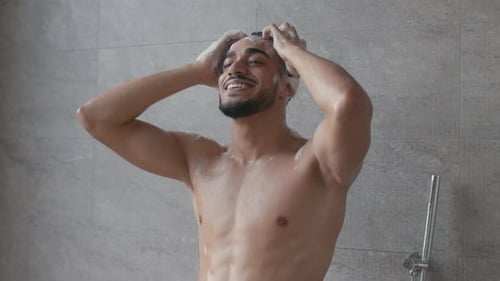 Handsome Man Washing Shampoo from Hair in Shower