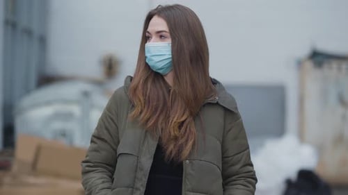 Woman Wearing Mask Standing Outside in Urban Setting