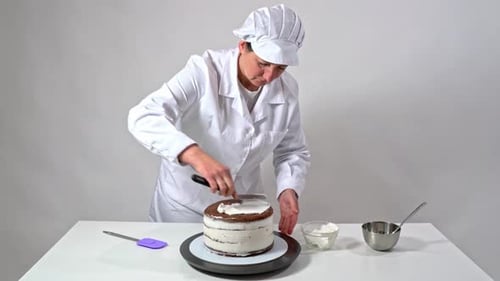 Baker Decorating Layered Cake with White Frosting
