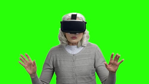 Senior Woman Immersed in Virtual Reality on Green Screen