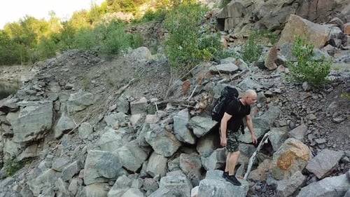 Aerial view of a young man walking along a giant rocky mountain. Traveler on the cliff.