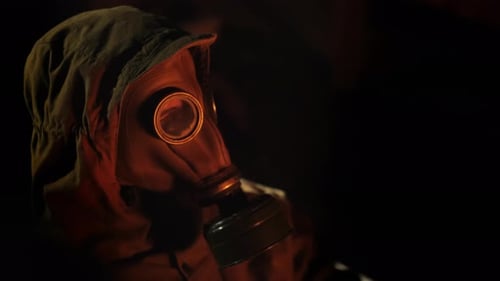 Side View of A Person in a Gas Mask Lights a Fire of a Fire