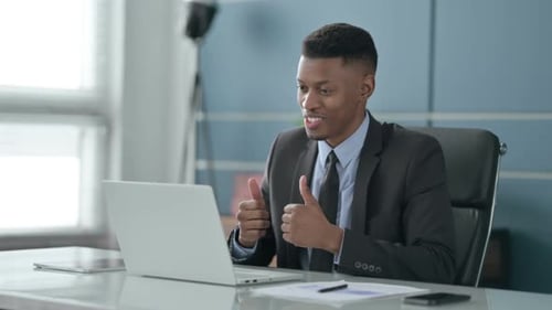 African Businessman Talking on Video Call on Laptop in Office
