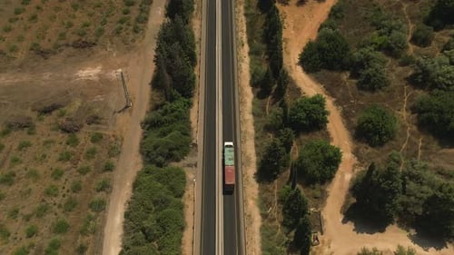 Truck loaded with Shipping Container driving on a rural highway, Aerial follow footage.