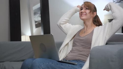 Woman with Laptop Celebrates Good News on Couch