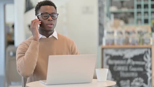 Young Adult Working on Laptop and Talking on Phone