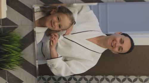 Mother Combing Daughter's Hair in Bathroom Mirror