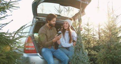 Couple Smiling at Phone with Christmas Tree