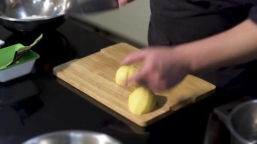 Person Cutting Potato into Pieces on Wood Board