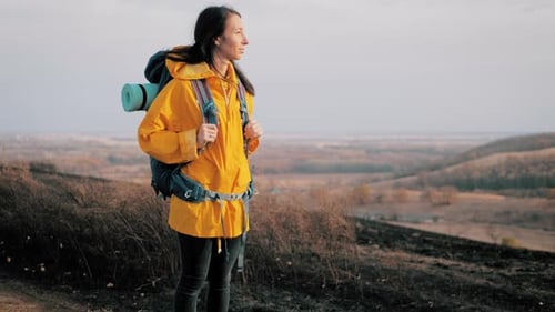 Female Hiker Stands on a Hillside Overlooking a Valley