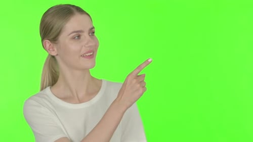 Young Woman Pointing on Green Screen Background