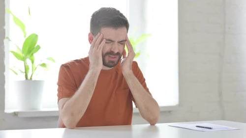 Young Man Having Headache While Sitting in Office