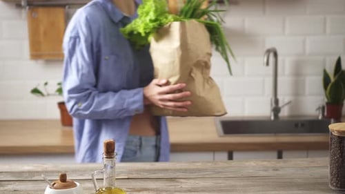 Mujer joven con bolsa ecológica de papel llena de productos orgánicos frescos. Ama de casa trae
