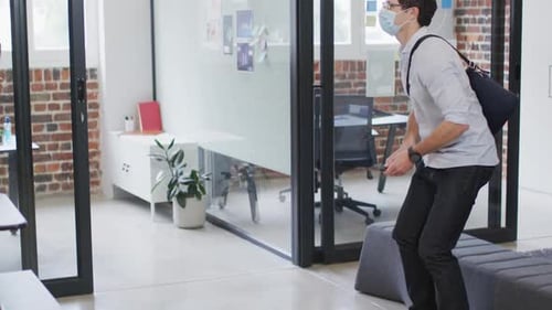 Man and woman wearing face masks greeting each other by touching their elbows at office