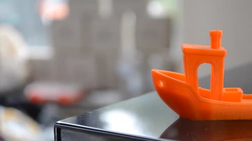 Orange Model Boat Sits on Shiny Table