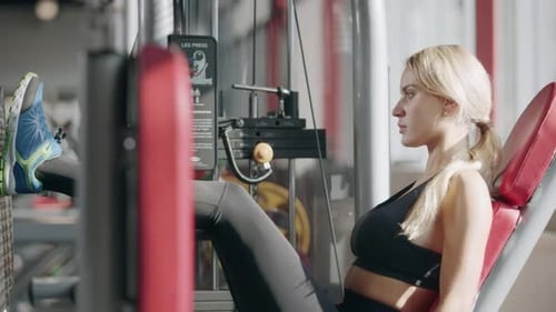 Pretty Fitness Girl Training Leg Press on Machine in Sport Club