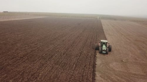 a Large Tractor Plows a Field