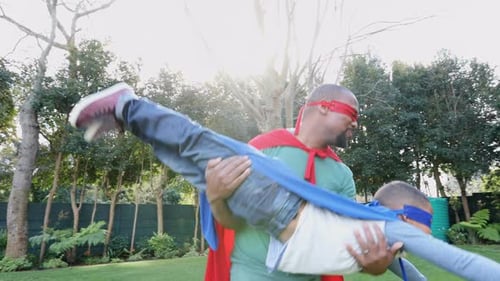 Father and Son Playing Superheroes in Garden
