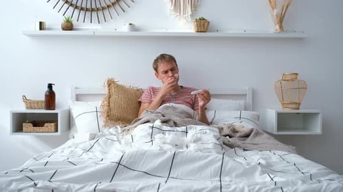 Young Adult Taking Medicine in Bed at Home