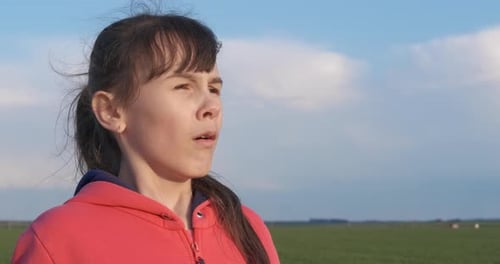 Young Girl Sneezing Outside in Rural Setting