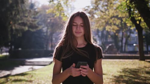 An Attractive Young Lady Using a Phone in Town. Medium Shot