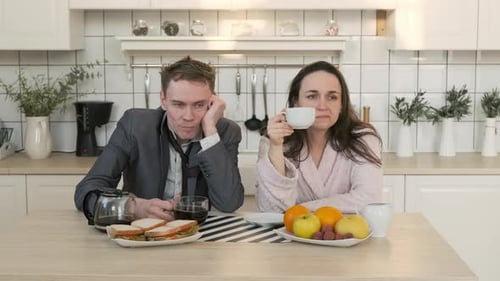 Tired Couple Having Coffee and Breakfast in Kitchen