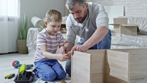 Father and Son Assembling Furniture Together at Home