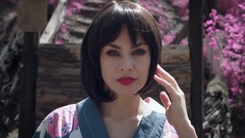 Steadicam-Aufnahme einer schönen kaukasischen Frau, die wie eine japanische Geisha gekleidet ist und draußen auf Sakura steht