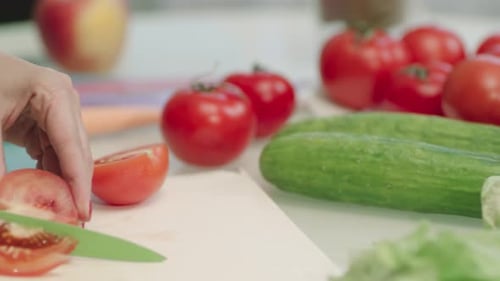 Person Slicing Fresh Tomatoes in Kitchen