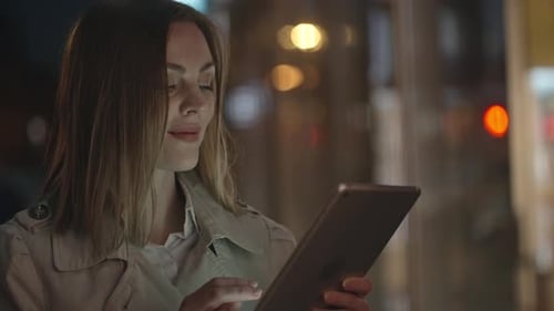 Woman Using Tablet at Night in Urban Setting