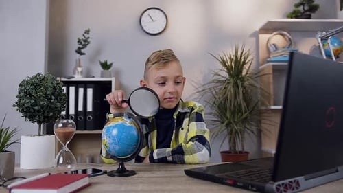 Child Studies Globe with Magnifying Glass at Desk