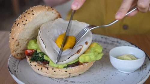 Close Up of Hands Cutting Organic Vegan Burger with Cutlery