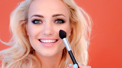 Mujer hermosa vivaz aplicar cosméticos