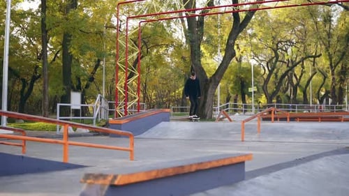 Slowmotion Shot of a Hipster Skateboarder Jumping on the Pipe in the Skatepark