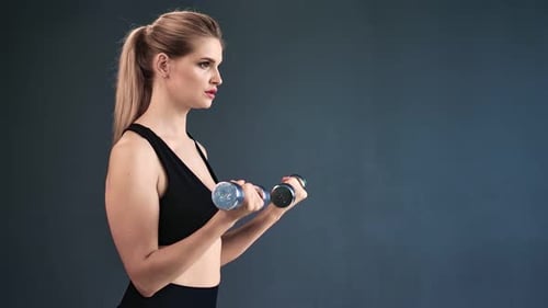 Sportswoman Lifting Iron Dumbbells During Biceps Muscles Workout Isolated