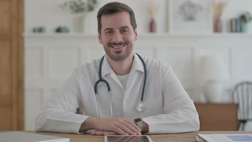 Young Doctor Smiling at Camera While Sitting in Clinic