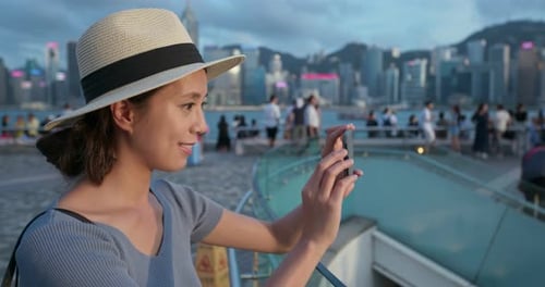Woman use of mobile phone to take photo in city of Hong Kong