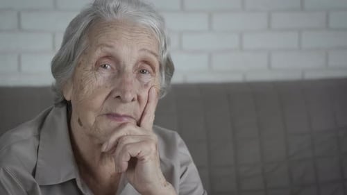 Pensive Senior Woman Resting Chin on Hand Indoors