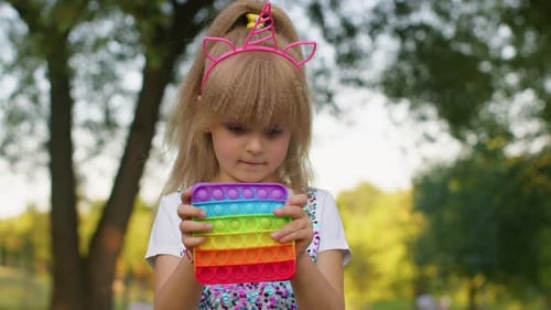 Child Plays with Pop-it Toy in the Park