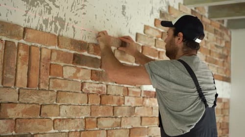 Man Installing Brick Wall with Laser Level
