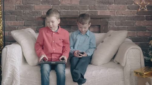 Boys Playing Games on Devices near Christmas Tree