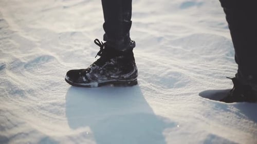 Closeup of Woman's Feet Walking on the Snow Desert at Sunset