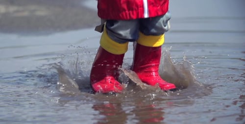 Child Splashing in Water Puddle at the Beach