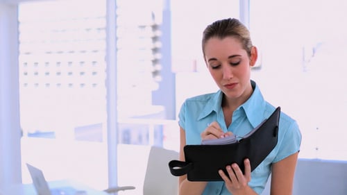 Woman Writing in Notebook in Bright Office