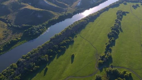 Aerial Footage of a Large River Surrounded By Green Fields and Hills