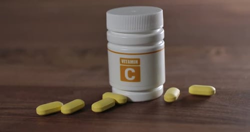 Vitamin C Bottle with Supplements on Dark Wood Surface